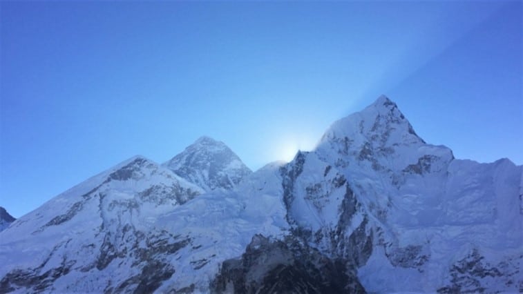 A view of the sun rising from behind Mount Everest